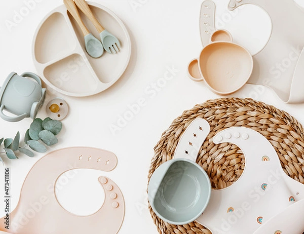Obraz Flat lay Baby food accessories. silicone bib, fork and spoon on light background.