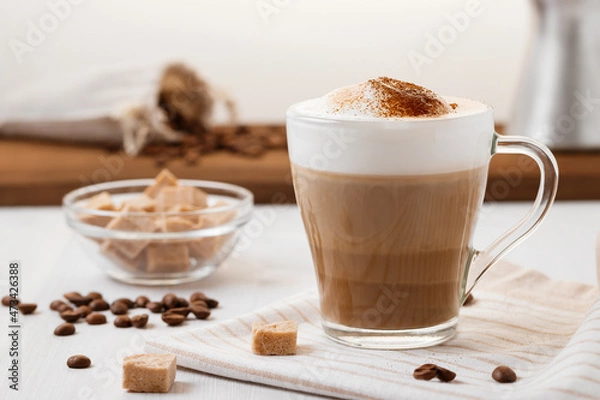 Fototapeta Latte coffee poured in layers with froth and a crispy chocolate top on a light kitchen table