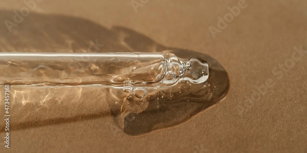 Fototapeta The texture of serum or oil with a pipette on a beige background.