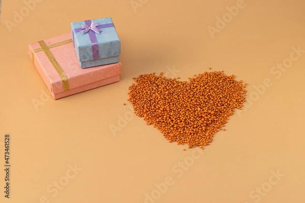 Obraz Heart shape with boxes of gifts on an orange background. The figurine is made of bright orange shiny beads. Valentine's day signs and symbols for copy space. Festive mockup.	