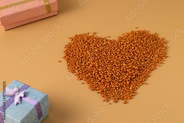 Obraz Heart shape with boxes of gifts on an orange background. The figurine is made of bright orange shiny beads. Valentine's day signs and symbols for copy space. Festive mockup.	