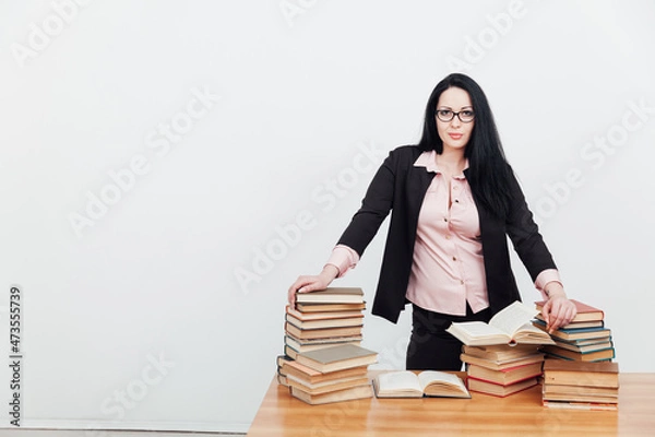 Fototapeta female teacher at a table with books for teaching
