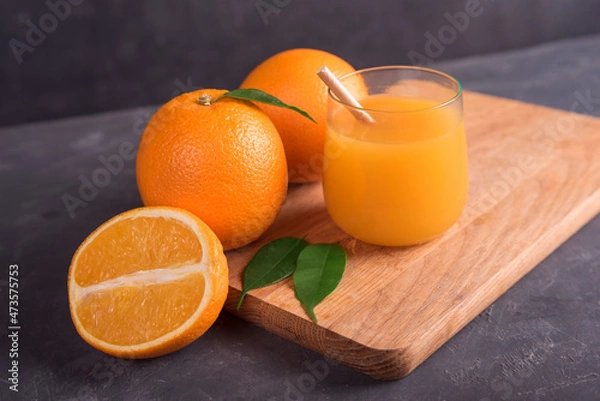 Obraz Glass of orange and juice and slice of orange fruit on wooden desk