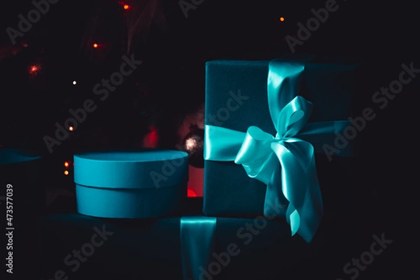 Fototapeta Turquoise gifts in a dark room, low key. Red background. A magical picture. Mystery and comfort. For a calendar or postcard