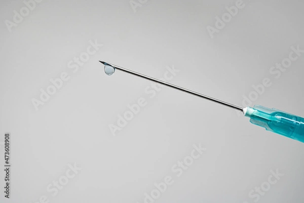 Fototapeta Needle of a syringe with a drop of the drug on the tip on a white background