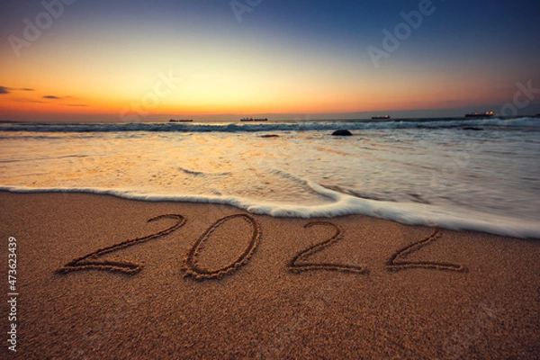 Fototapeta Happy New Year 2022 concept, lettering on the beach. Sea sunrise