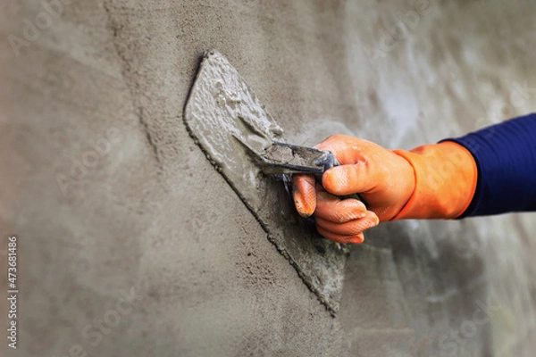 Fototapeta Plastering concrete to create industrial worker wall background with plastering tools