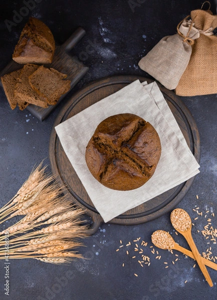 Fototapeta round bread on a wooden board, sliced ​​bread and wheat
