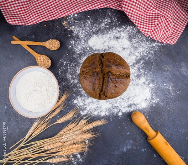 Fototapeta freshly baked homemade bread on the table with flour, rolling pin and red napkin