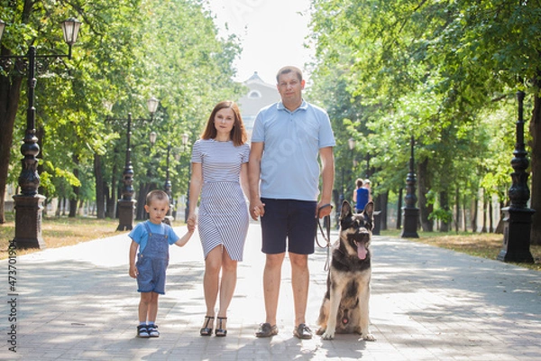 Fototapeta A family of three on a walk with the dog. German Shepherd