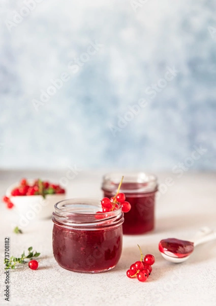 Obraz Glass jar with red currant jelly or jam and fresh red currant berries.