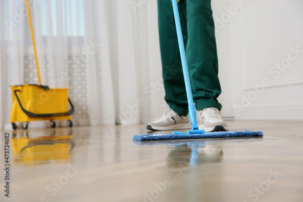Obraz Professional janitor cleaning parquet floor with mop indoors, closeup. Space for text