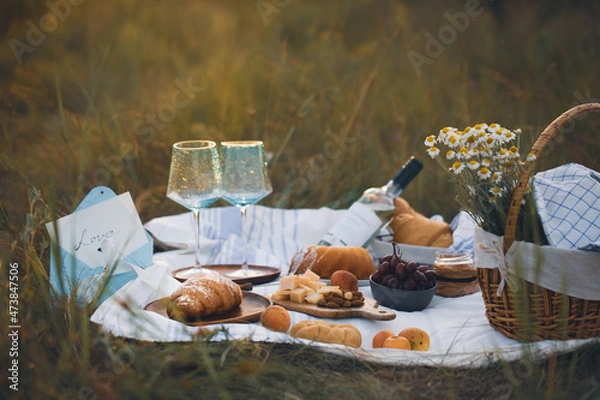 Obraz A picnic on the grass with wine and croissants. breakfast with a croissant. French breakfast. Food on the street. Croissants in nature. Romantic breakfast. Beautiful breakfast with champagne 