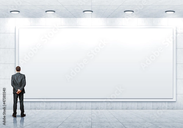 Fototapeta Business person standing near a blank billboard