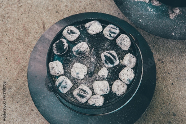 Fototapeta dutch oven covered with light gray coals for cooking in it