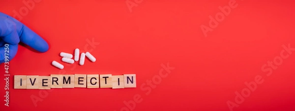 Fototapeta Ivermectin on colored red paper texture background. Ivermectin antiparasitic medication. Off label approved medicine drugs use. Covid-19 therapy. Pharmacy concept. Copy space. Mock up design template