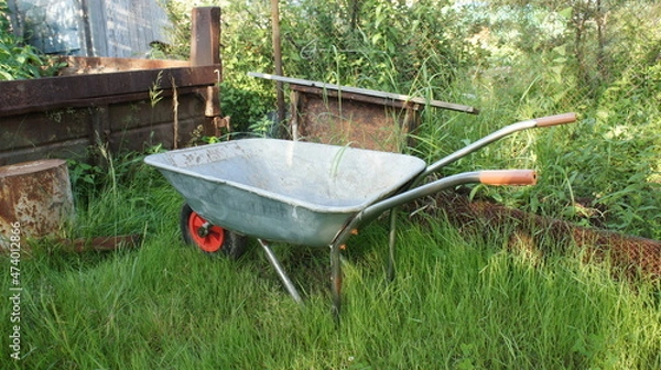 Obraz Garden wheelbarrow on green grass, rustic landscape