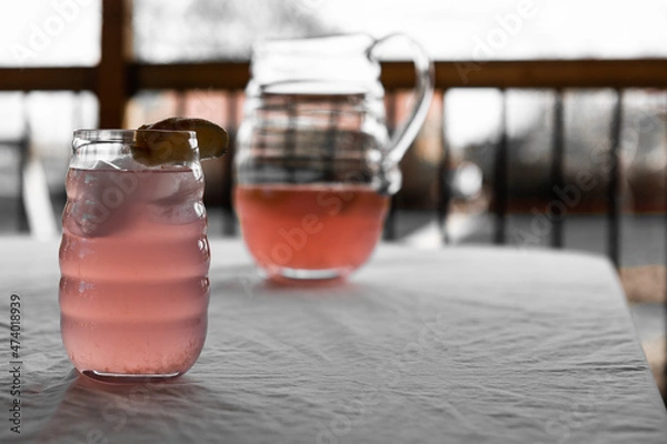 Fototapeta Close up of Pink lemonade with lemon wedge on table
