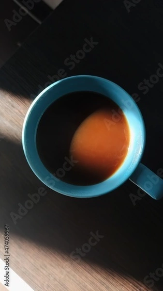 Fototapeta A coffee mug with the sun shining on it. Top view.