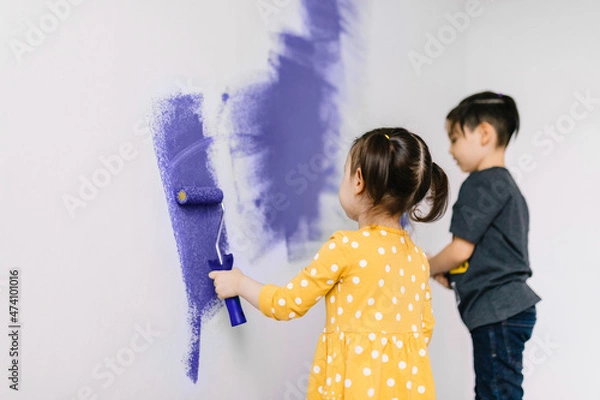 Fototapeta Children paint the wall in a fashionable color Very Peri - the color of 2022