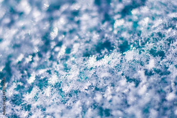 Fototapeta Snowflakes photographed close-up on a turquoise and blurred background.