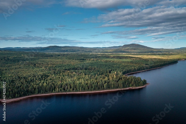 Fototapeta Green forest and lakeshore at Lake Siljan from above with blue sky in Dalarna, clouds in sky, Sweden.
