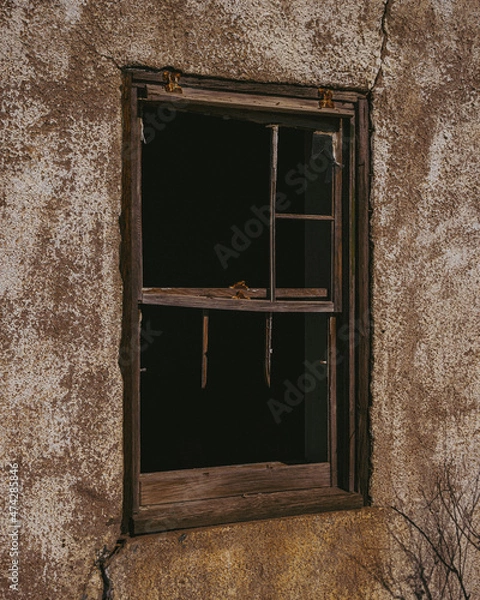 Fototapeta Broken window of an abandoned stucco house

