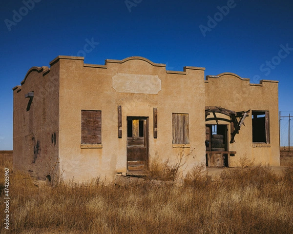 Fototapeta Old abandoned stucco building with broken windows and wooden doors