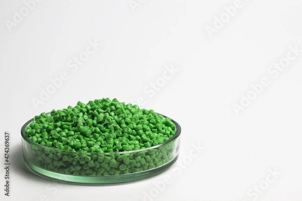 Fototapeta Green  granules of polypropylene or polyamide on a white background. Plastics and polymers industry. Copy space. Glass petri dish, flask, volumetric glassware, test tube.