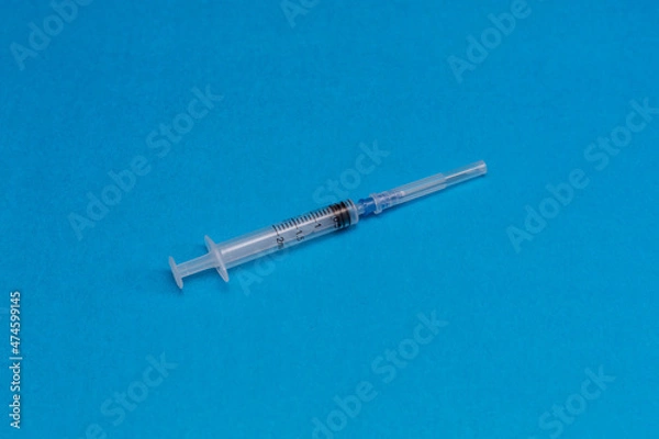 Fototapeta Disposable syringe on a blue background.