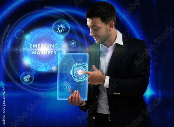 Fototapeta Business, Technology, Internet and network concept. Young businessman working on a virtual screen of the future and sees the inscription: Emerging markets