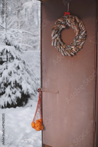 Fototapeta Tangerines in a bag are hanging on an old door.