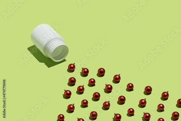 Obraz Christmas decoration creative idea with red baubles and pill package on bright green background. Minimal visual composition, abstract surreal concept.