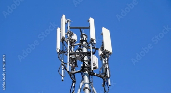 Obraz Telecommunication tower of 4G and 5G cellular. Macro Base Station. 5G radio network telecommunication equipment with radio modules and smart antennas mounted on a metal against blue sky background.
