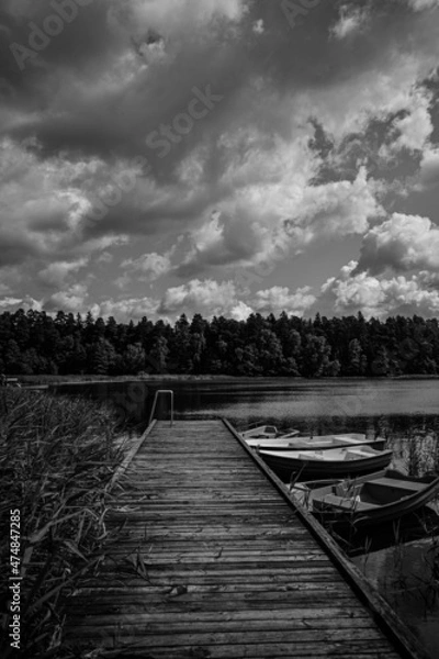 Fototapeta wooden jetty, with boats on the right and a lake in the background