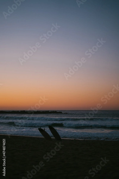 Fototapeta Silhouette of two surf boards on the shore of San Sebastian beach after the sunset