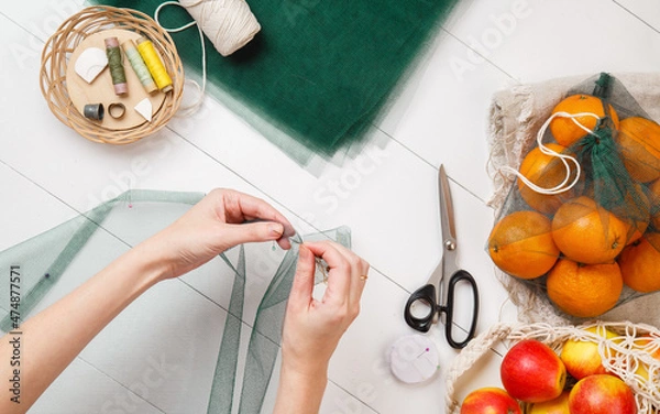 Obraz Woman Sews shopping bags instead of plastic bags top view. DIY Reusable mesh shopper. Handmake of Eco bags for shopping in grocery store. Fresh fruits. Eco-friendly shopping. Zero waste. Plastic free