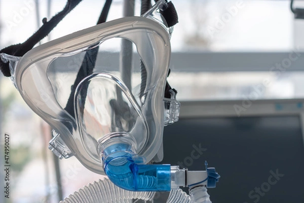 Fototapeta Non-invasive ventilation face mask, close up view, on background medical ventilator in ICU in hospital.