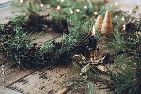 Obraz Handmade Christmas wreath with pinecones and red berries on rustic wood table, Countryside advent Christmas celebration with fir garland, candle, and Christmas lights