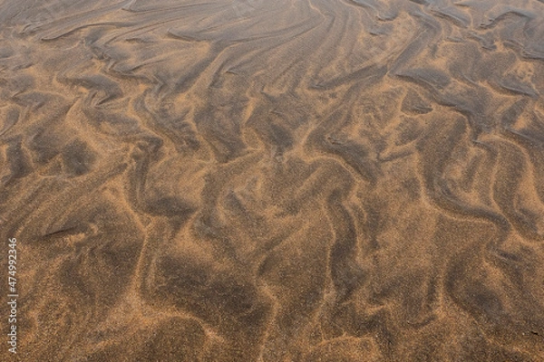 Fototapeta Amazing natural sand pattern made by wind and water on a sandy beach. Unique design for creative purpose. Design background. Random shapes on a dark and light sand surface