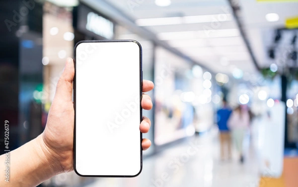 Obraz Close-up of female use Hand holding smartphone with empty blank white screen blurred images touch of Abstract blur of inside shopping complex background,shopping online concept.