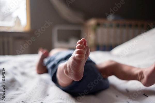Obraz Charming legs of a newborn baby close-up lying on the bed in the bedroom