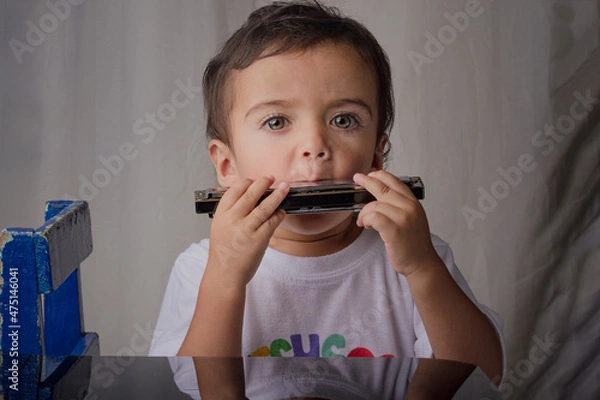 Fototapeta portrait of little boy making music with a harmonica