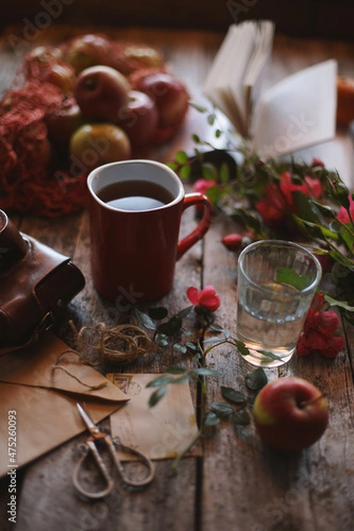Fototapeta A mug of tea on a wooden background, old envelopes, flowers in retro style.