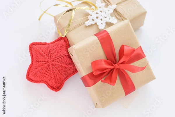Fototapeta Christmas and New Years decorated gifts. Gift box wrapped in kraft paper with red ribbon. Red knitted heart. Box with jute cord and crocheted snowflake