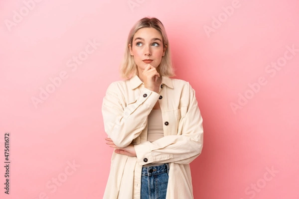 Fototapeta Young caucasian woman isolated on pink background thinking an idea while looking up