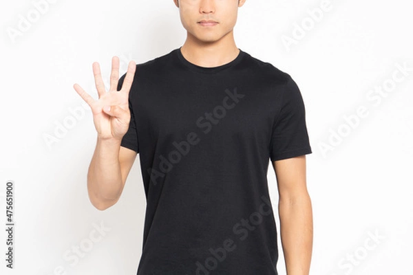 Fototapeta 白い背景の前に立って、手で数字の4を表す黒いTシャツを着ている男性