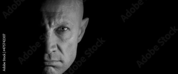 Obraz The male face is half lit, black and white photo. Concept: killer in the dark. Night ghost.