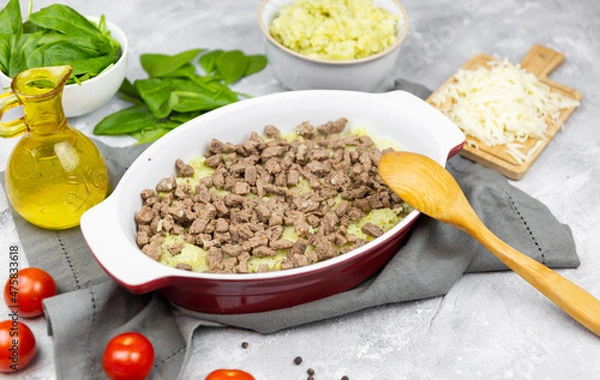 Fototapeta putting minced meat in the potato casserole