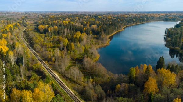 Fototapeta A beautiful view from above of the autumn forest and lake, the view from the drone. The railway passes through the forest.